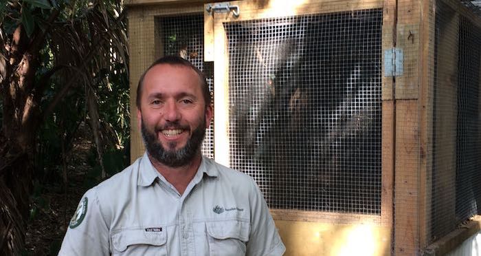 Parks Australia Manager, Craig Doolan next to the cage where Norfolk Island green parrot fledglings were held before being sent to Phillip Island.